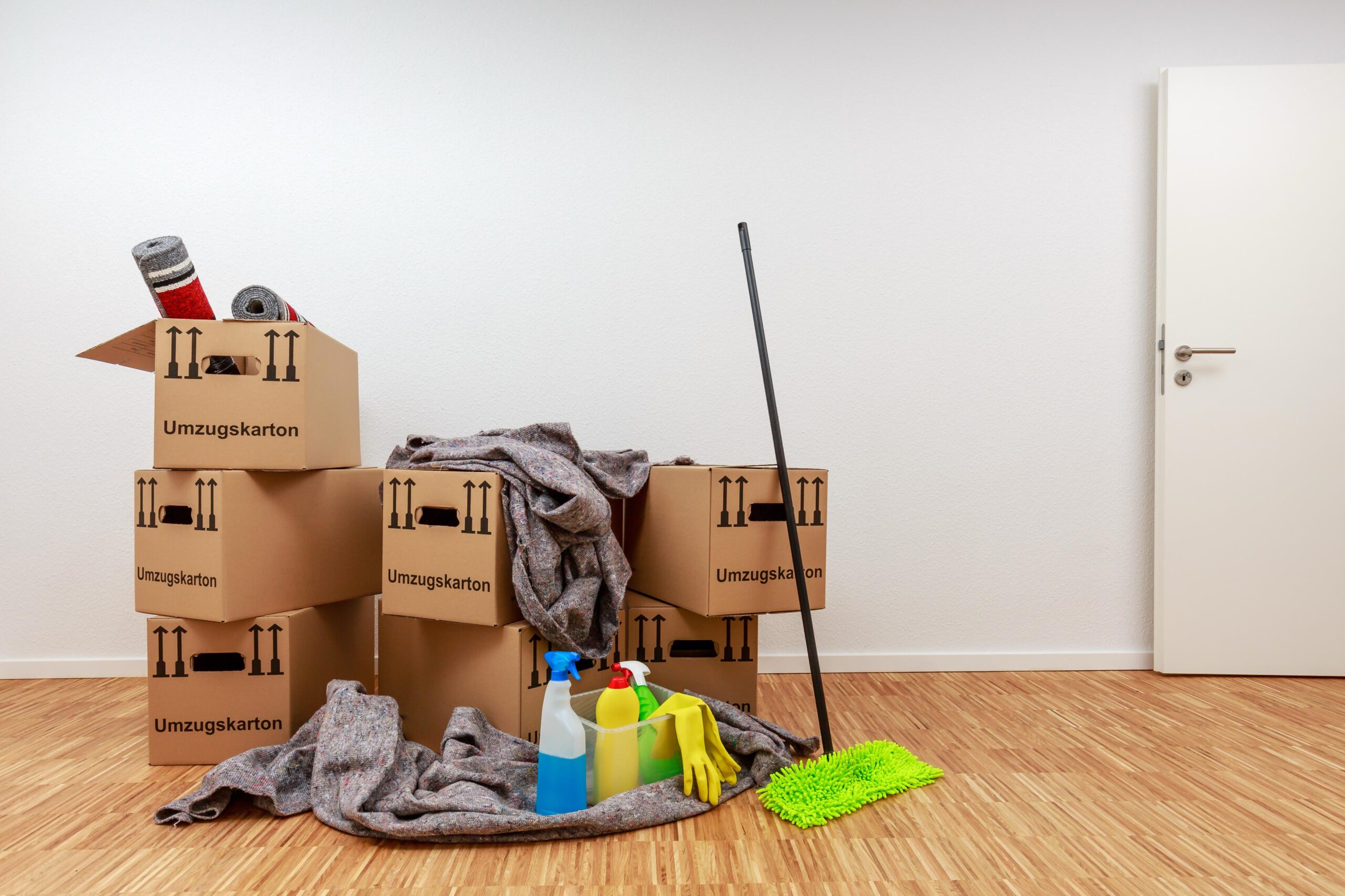 Umzugskartons und Reinigungsutensilien stehen in einem leeren Raum und zeigen eine Firmenauflösung in Witten mit vorbereiteter Übergabe.